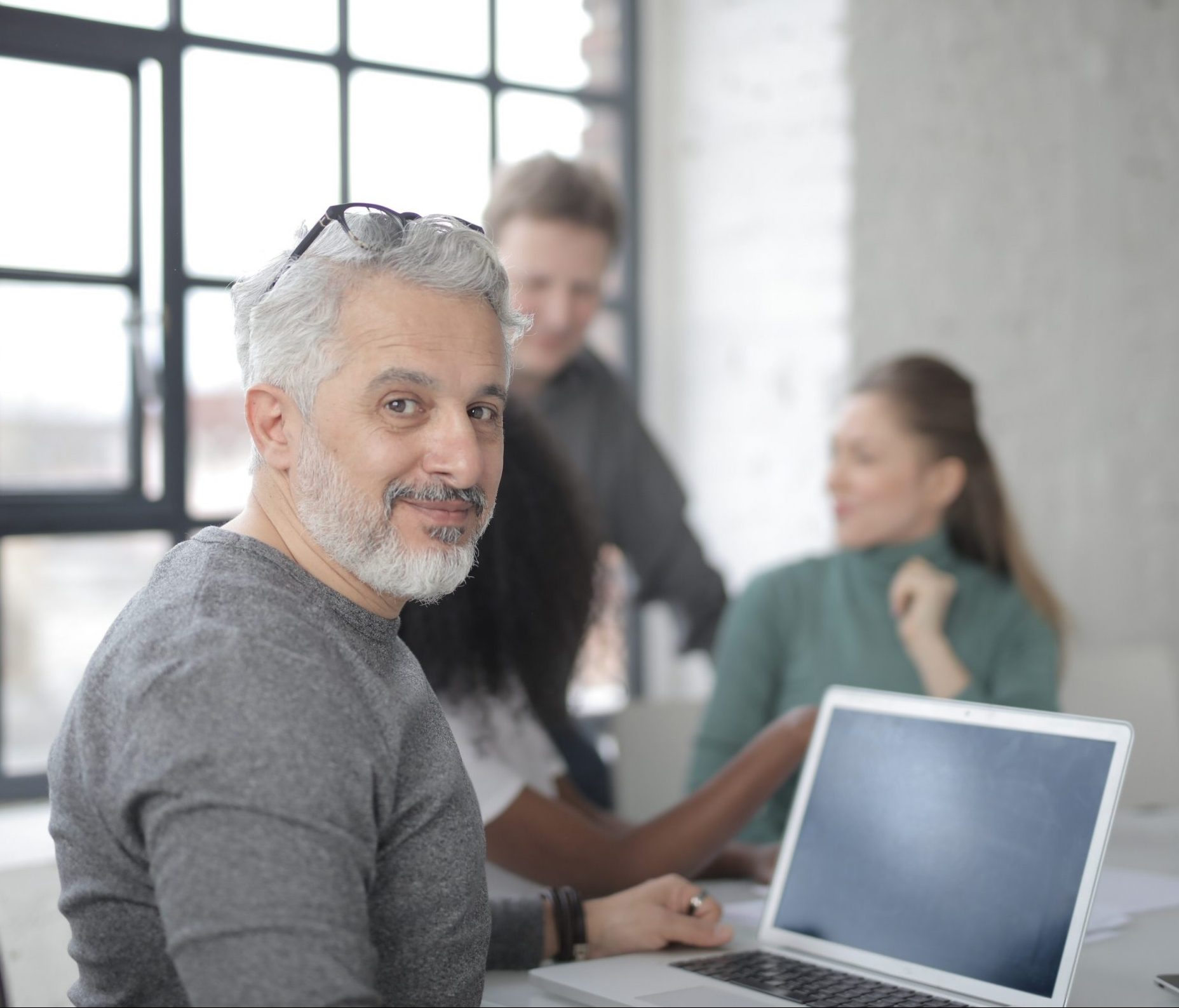 cheerful-male-worker-sitting-with-laptop-and-multiethnic-3865577